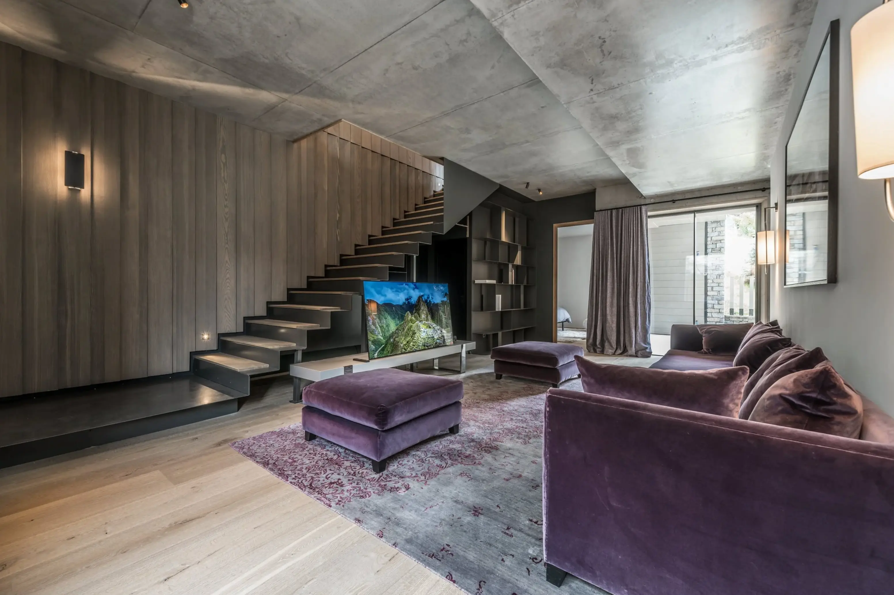 Salon moderne avec escalier flottant, canapé violet et télévision au centre