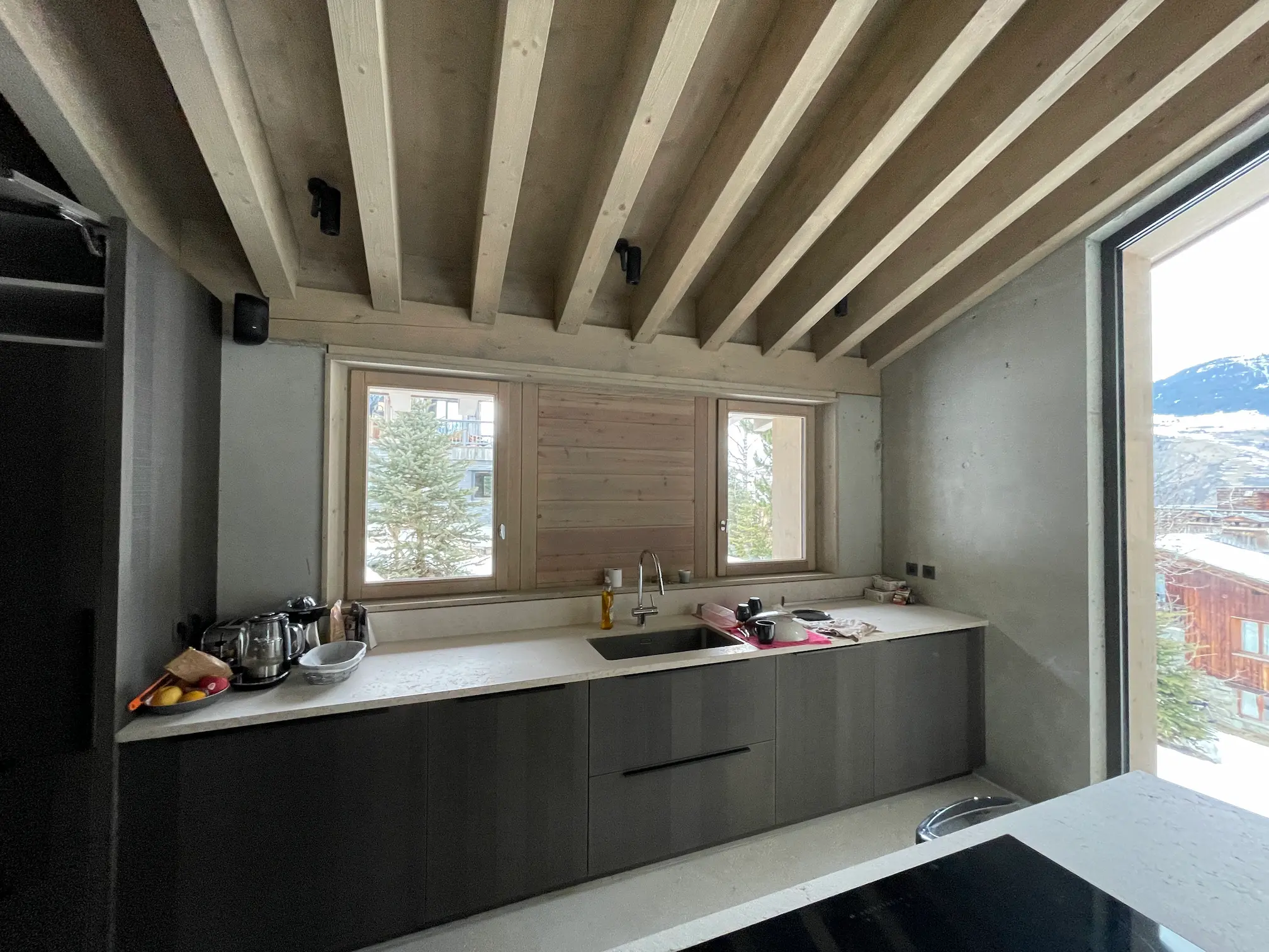 Cuisine moderne avec îlot, évier sous la fenêtre et vue sur la montagne